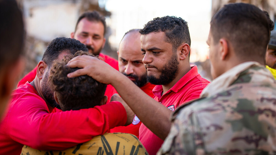 Group of men supporting each other during rescue operations of Libya floods.