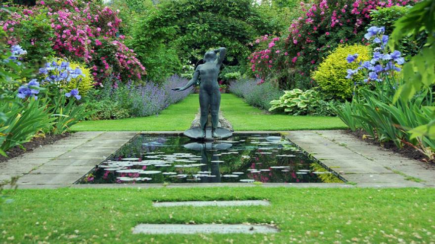 Statue in water surrounded by borders of flowers at Shepherd House one of the British Red Cross open gardens.