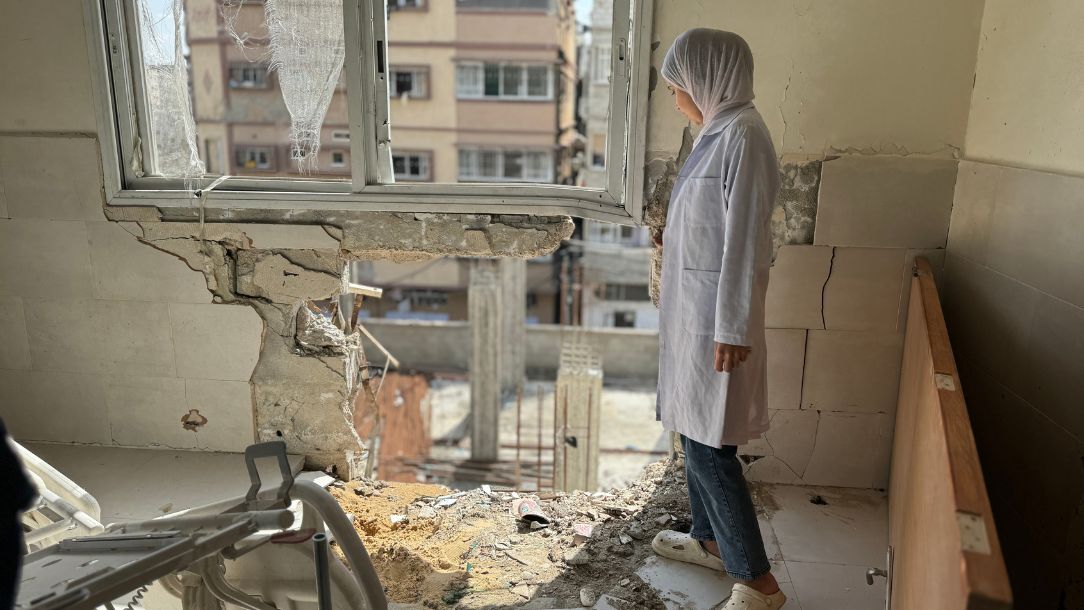 A woman stands in a badly damaged building in Gaza, staring in disbelief at the damage.