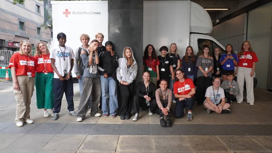 A group of more than 20 young people standing in a line outside the British Red Cross office in central London.