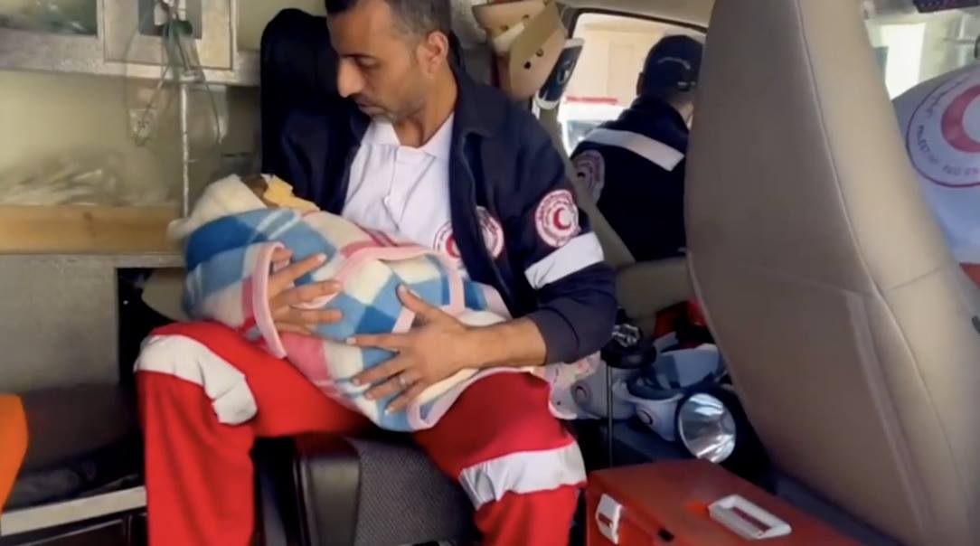 A Palestine Red Crescent ambulance worker takes an injured baby for hospital treatment due to fighting in Gaza.