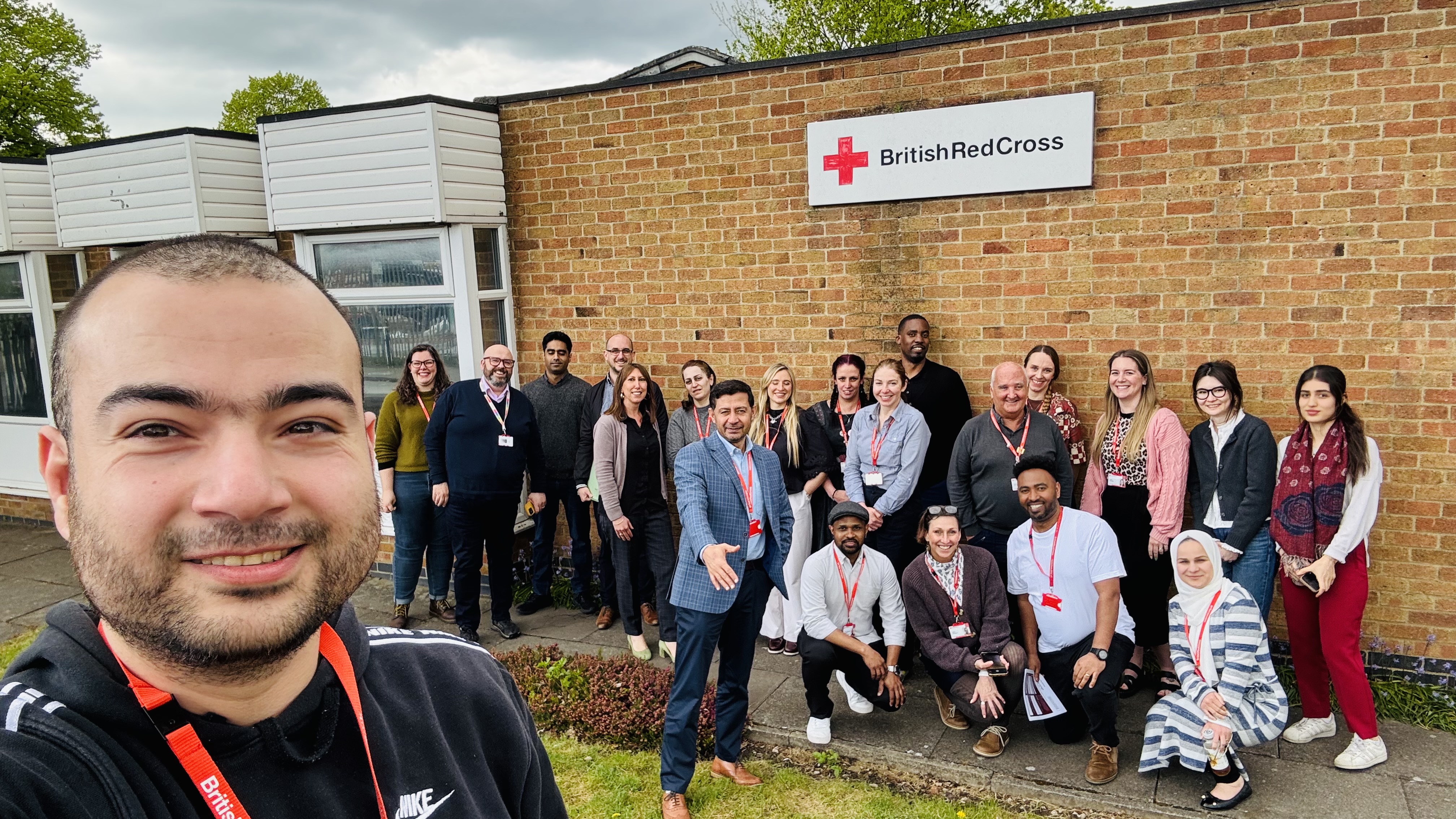 A group of people pose for the camera in front of a British Red Cross building