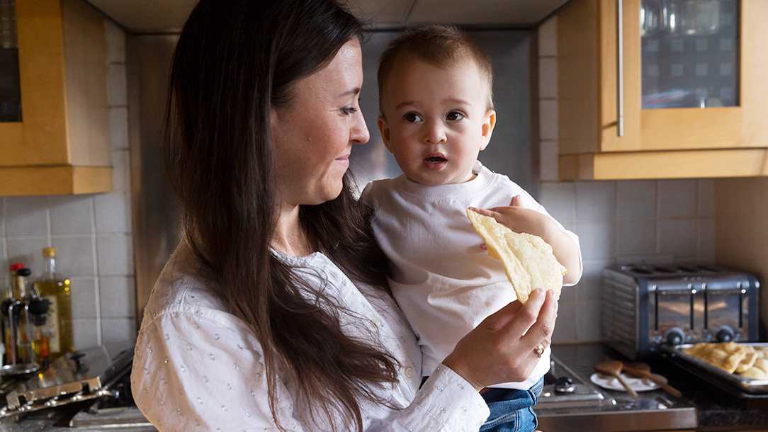 Mother holds baby in kitchen of home.