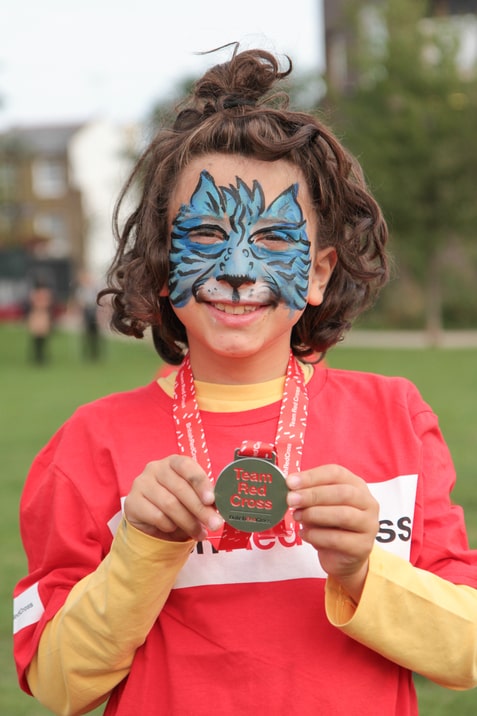 Girl with face painted, shows off her medal