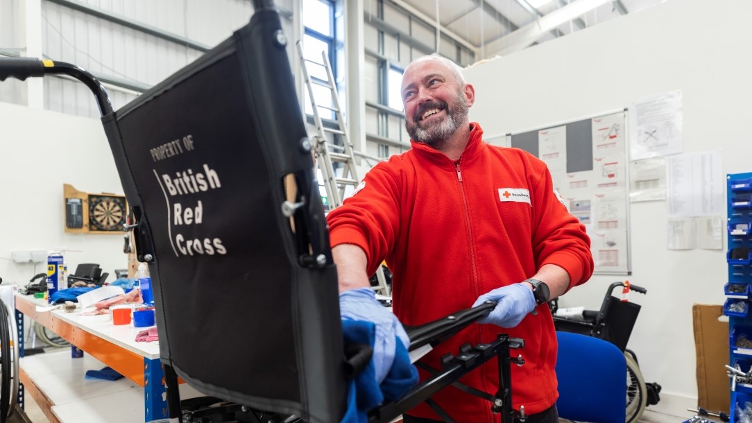 A photograph of a British Red Cross worker cleaning a British Red Cross wheelchair for hire.