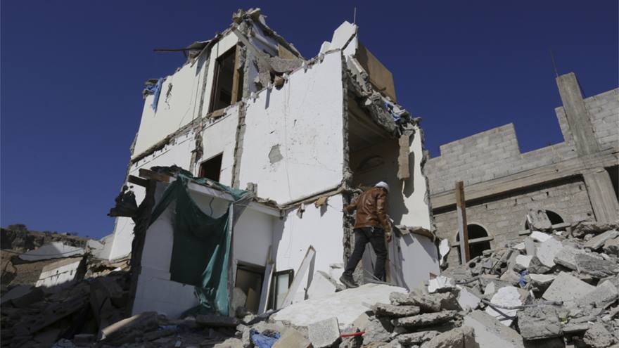 A man walks over the rubble of a bombed building.